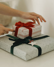 Two wrapped gifts with red and green ribbons on a light surface.