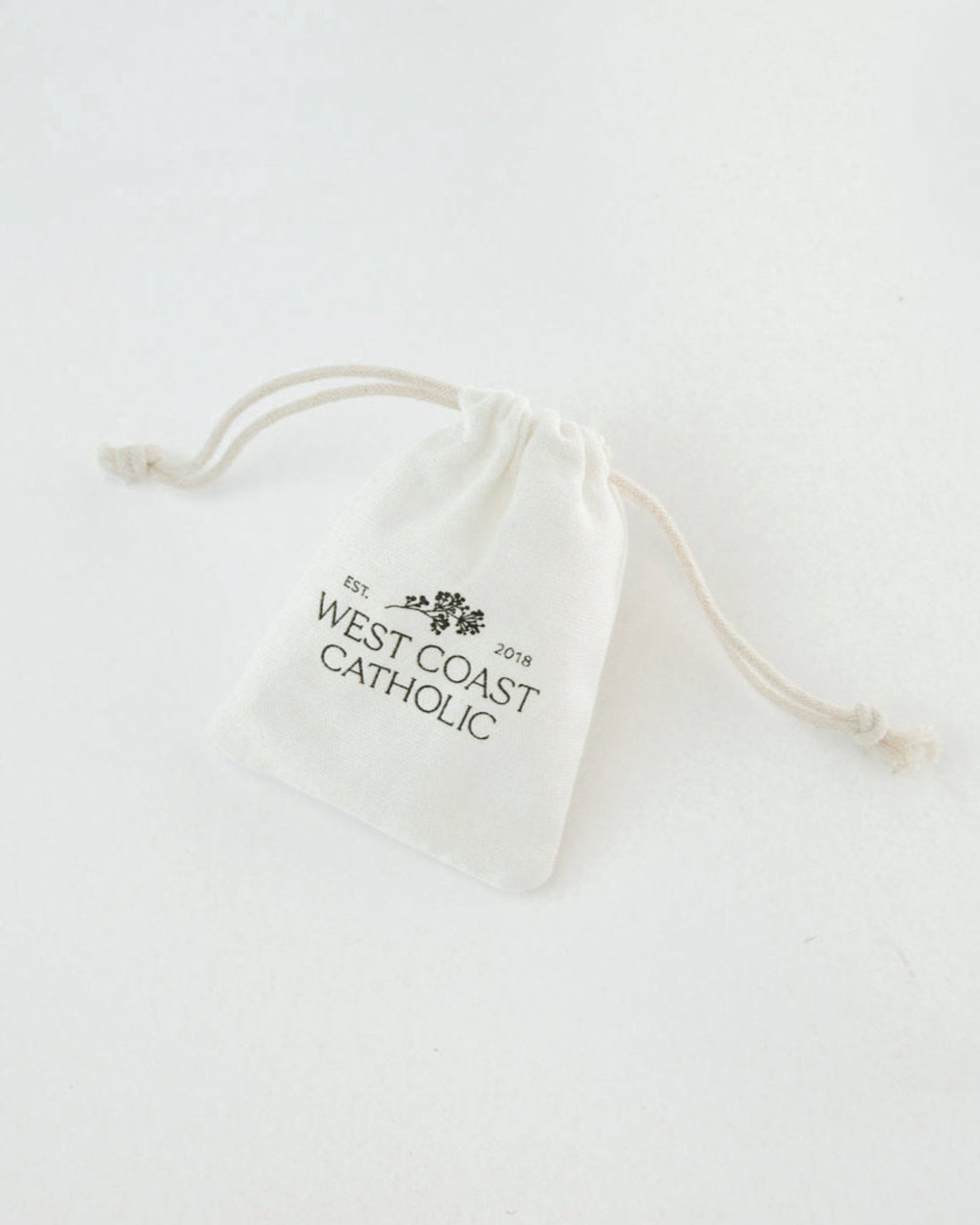 White drawstring bag with 'West Coast Catholic' text on a white background