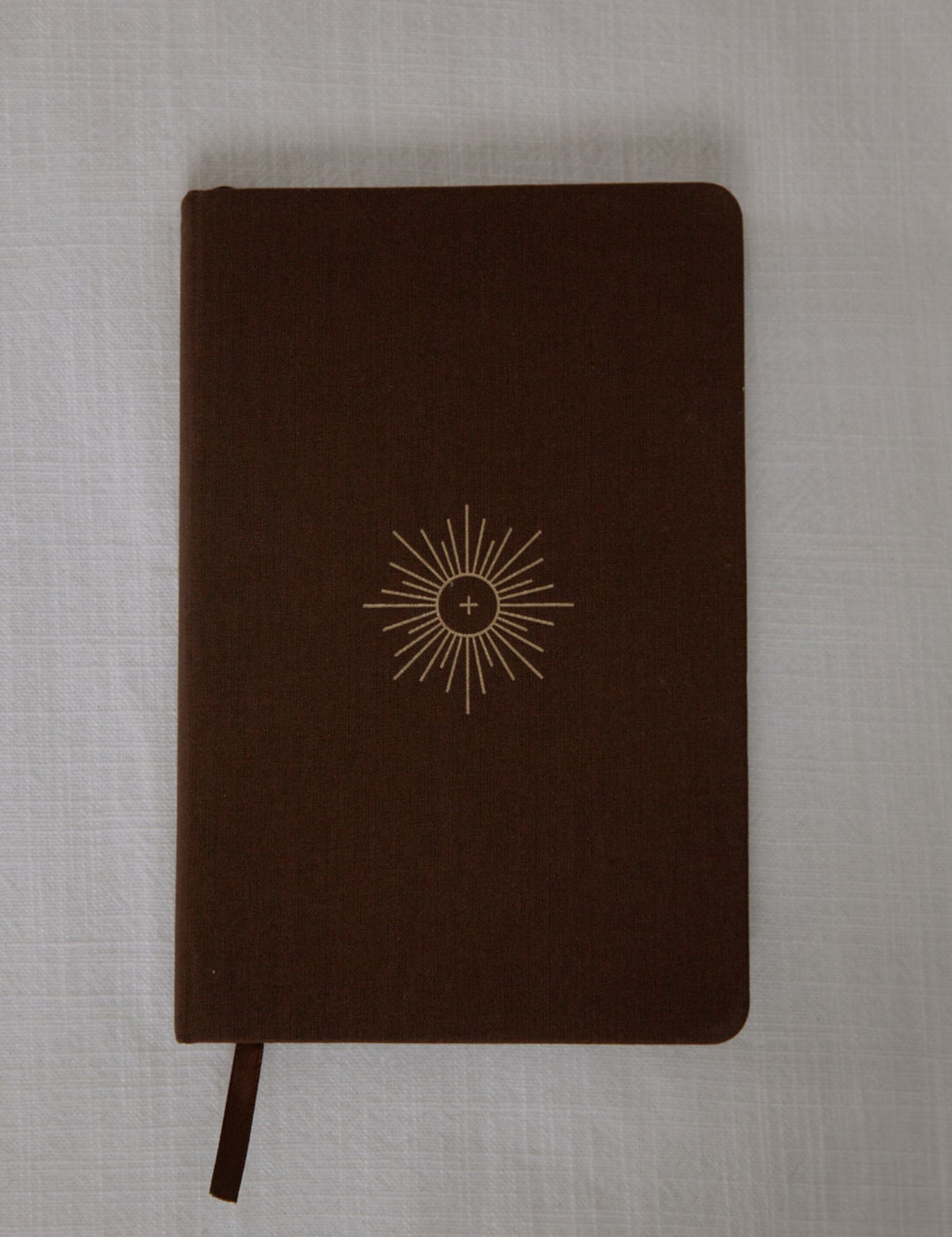 Brown notebook with a sun design on a textured gray background