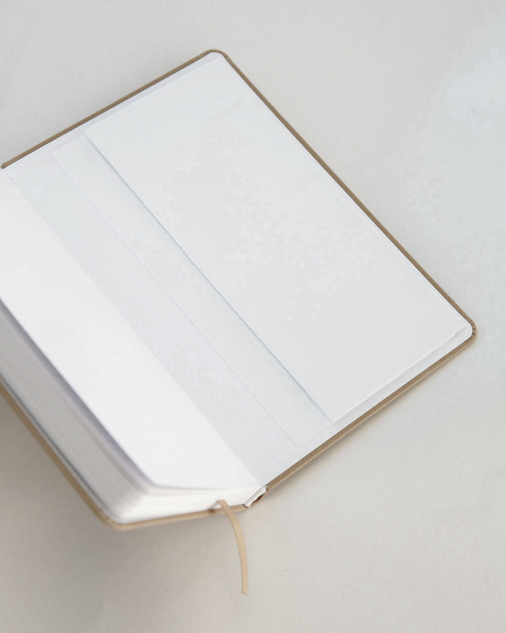 Open notebook with white pages and back pocket on a light gray background