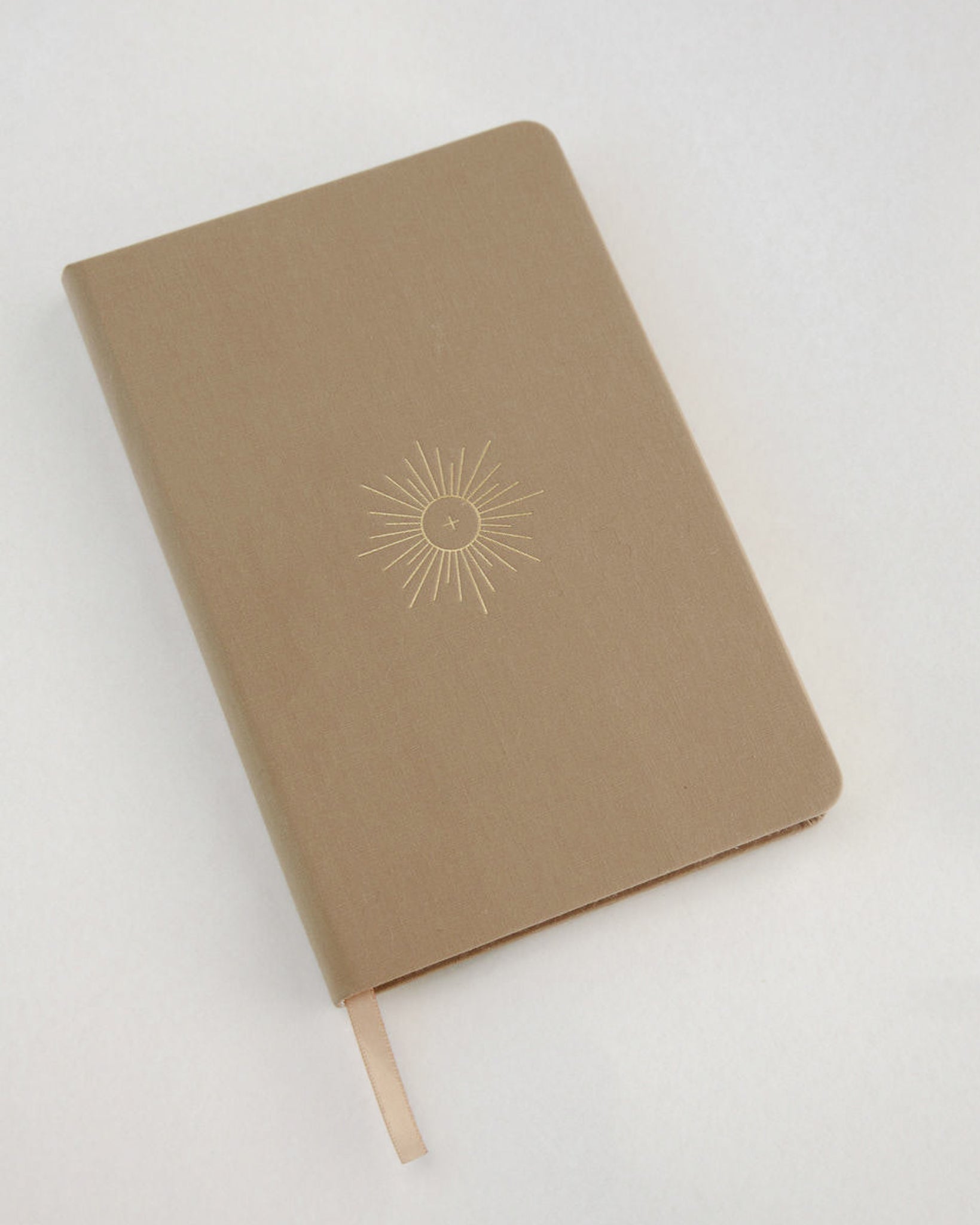 Brown notebook with linen cover and a sun design on a white background