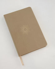 Brown notebook with linen cover and a sun design on a white background