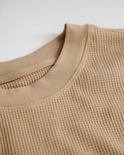 Close-up of a beige textured sweater on a light background
