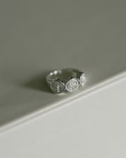 A silver St. Benedict ring, resting on a clean, light gray surface.