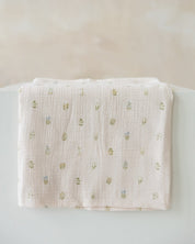 light pink muslin baby swaddle with a small embroidered floral pattern