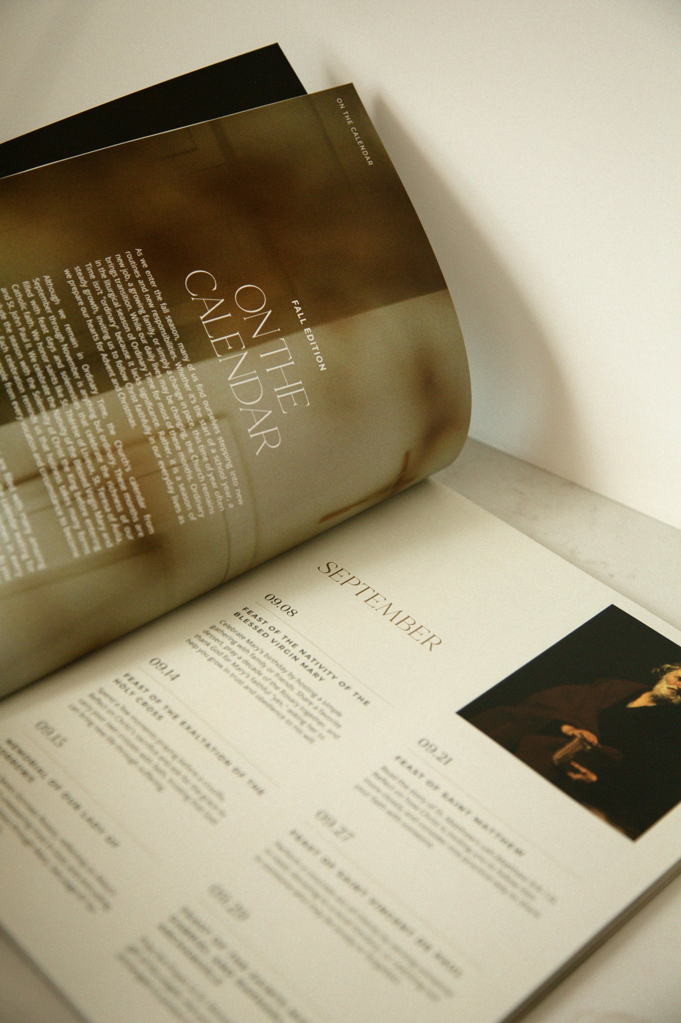 Heaven & Home magazine open to the, On the Calendar, liturgical living calendar --fall edition, featuring September, October, and November Catholic feast days on a marble counter top.