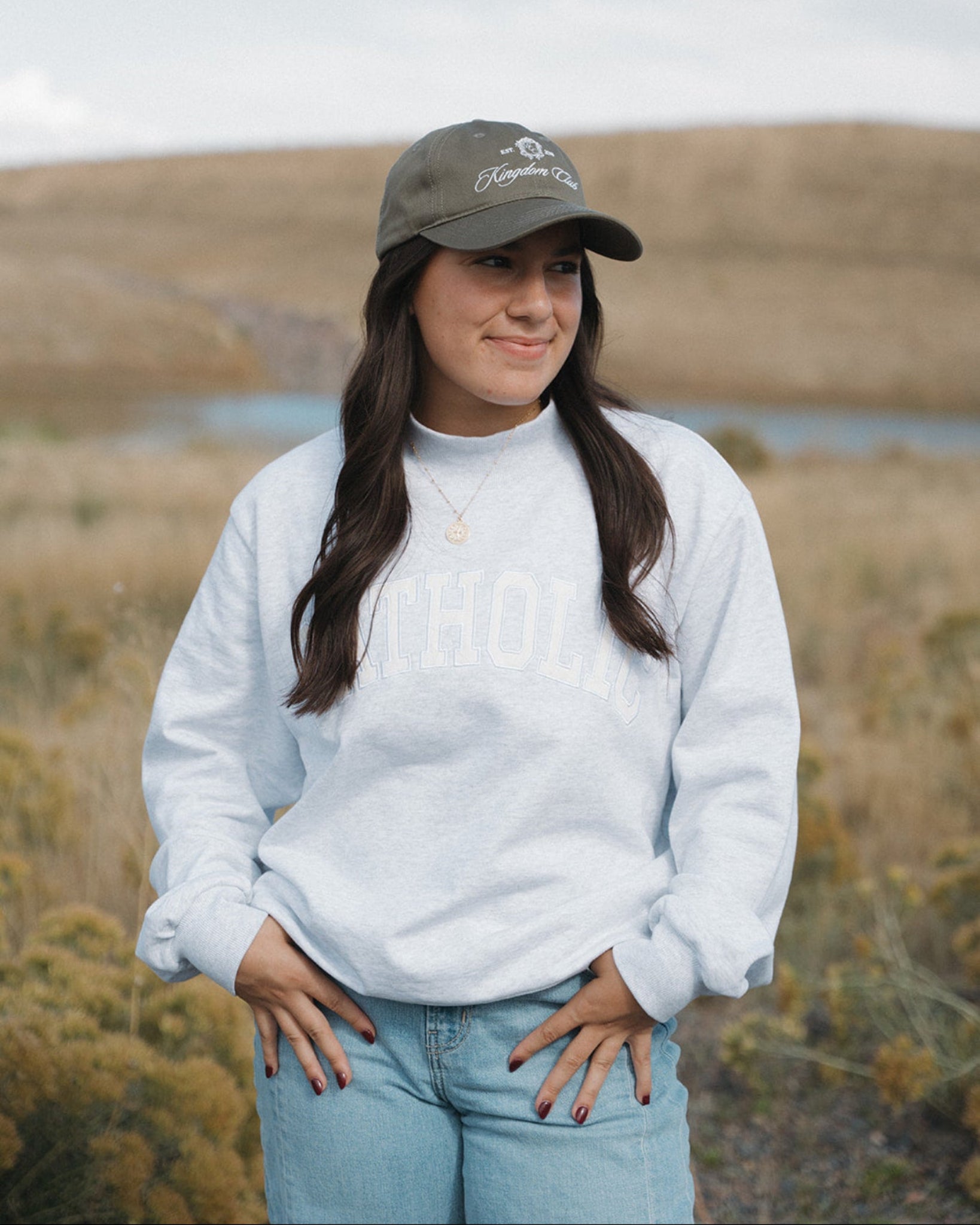 Woman wearing a white sweatshirt and cap in a natural landscape