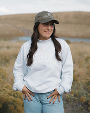 Woman wearing a white sweatshirt and cap in a natural landscape