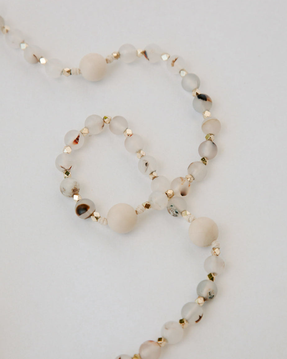 Necklace with white beads and gold accents on a light gray background