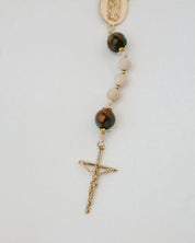 Rosary with stone beads and gold crucifix on a white background