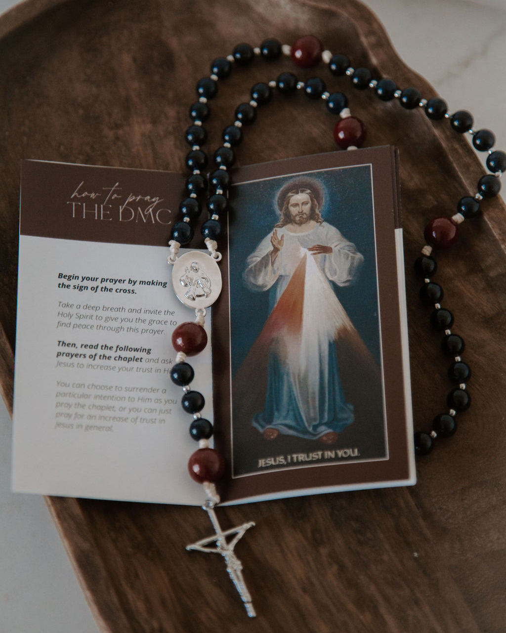 Rosary with prayer card on a wooden surface