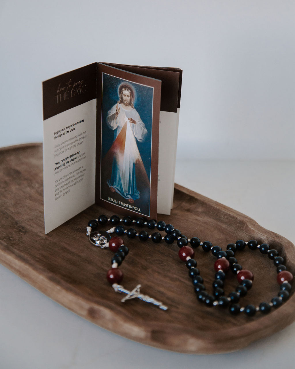 Open book with a religious illustration on a wooden tray with a rosary