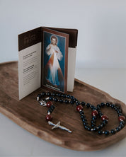 Open book with a religious illustration on a wooden tray with a rosary