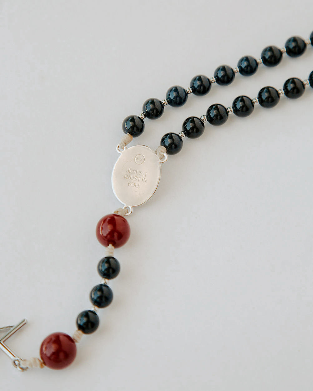 Rosary with black and red beads on a light gray background