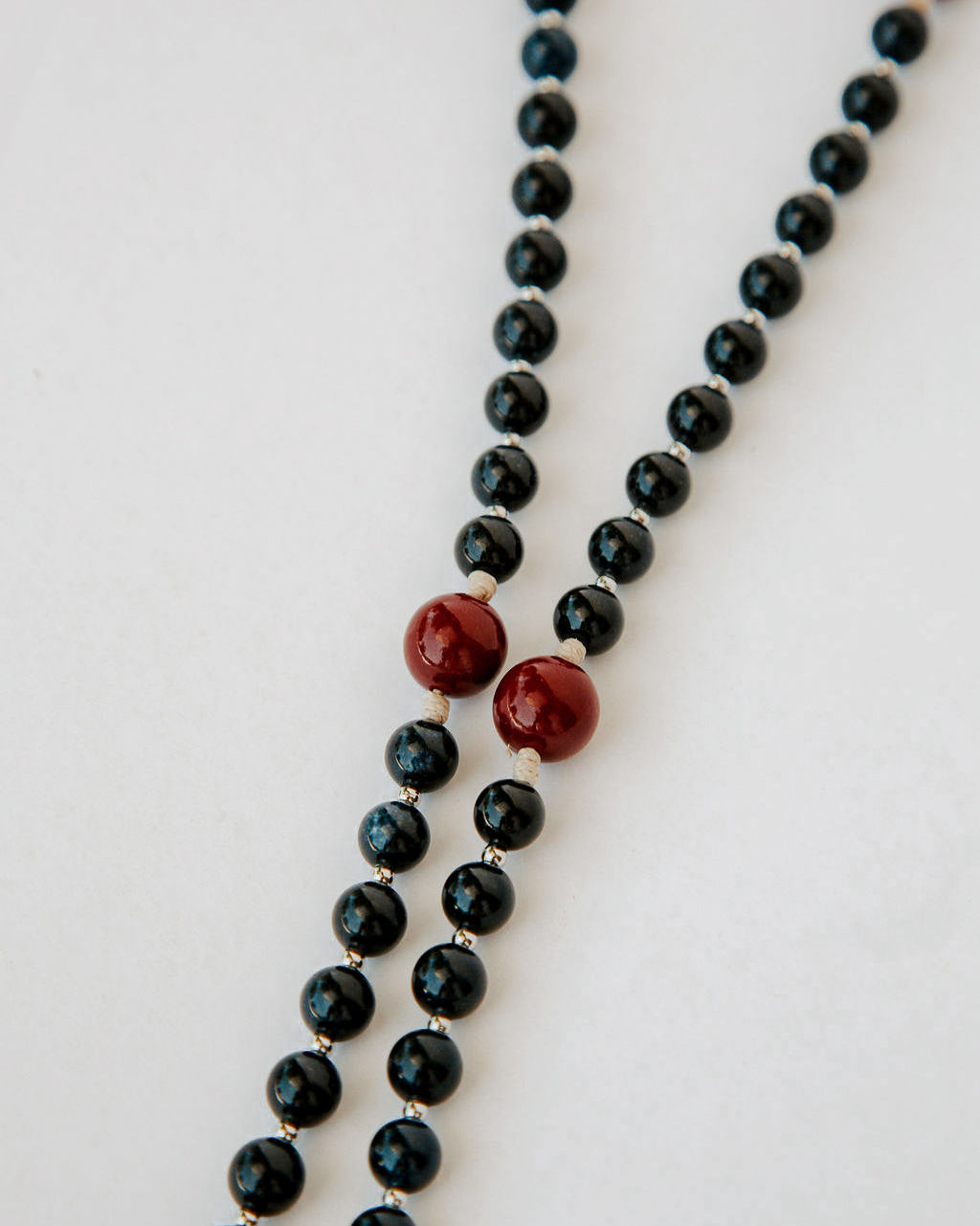 Rosary with black beads and red accents on a white background