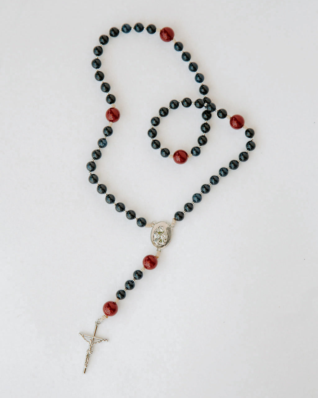 Rosary with black and red beads on a white background