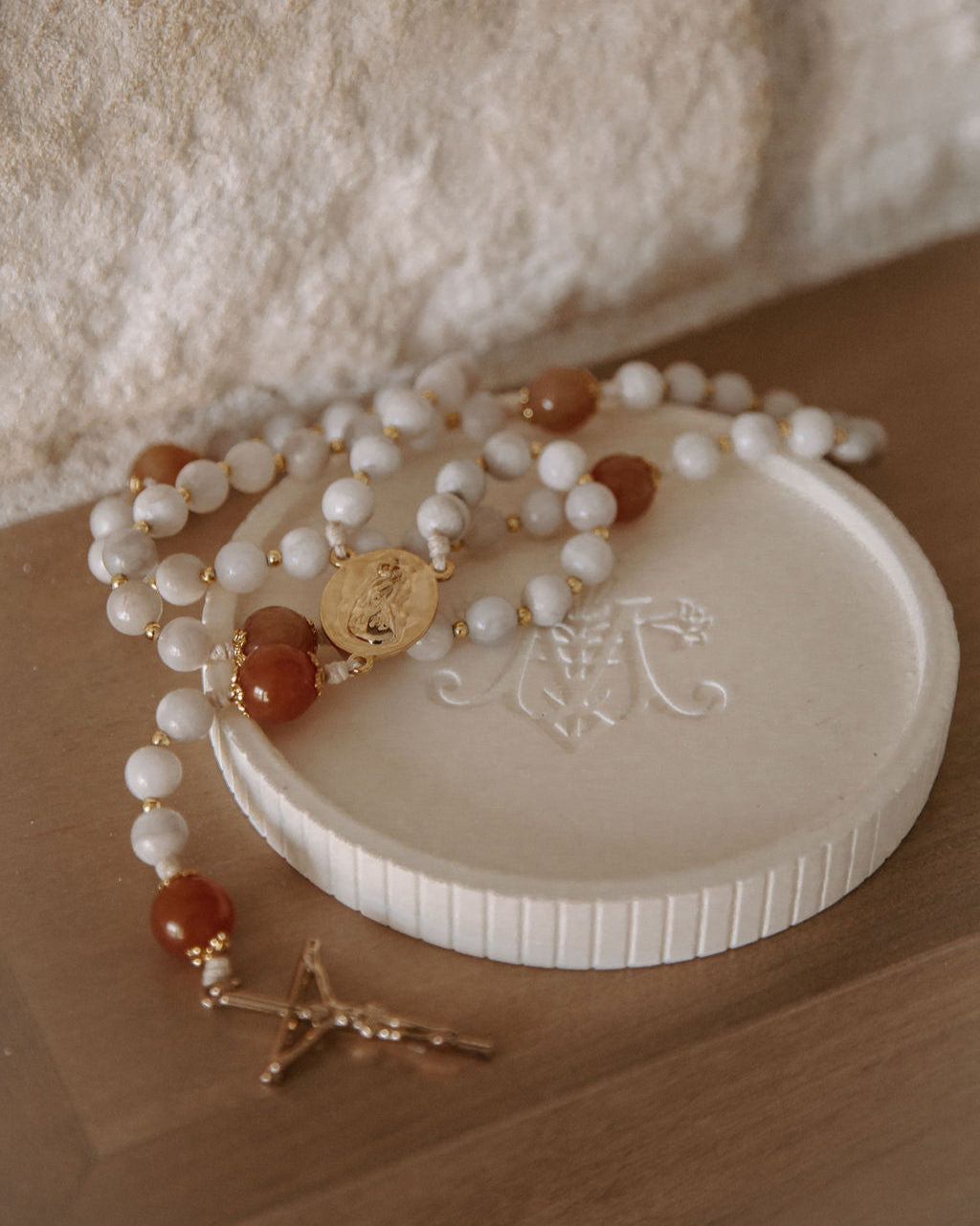 White beaded rosary with gold accents on a white stone surface