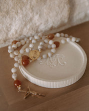 White beaded rosary with gold accents on a white stone surface