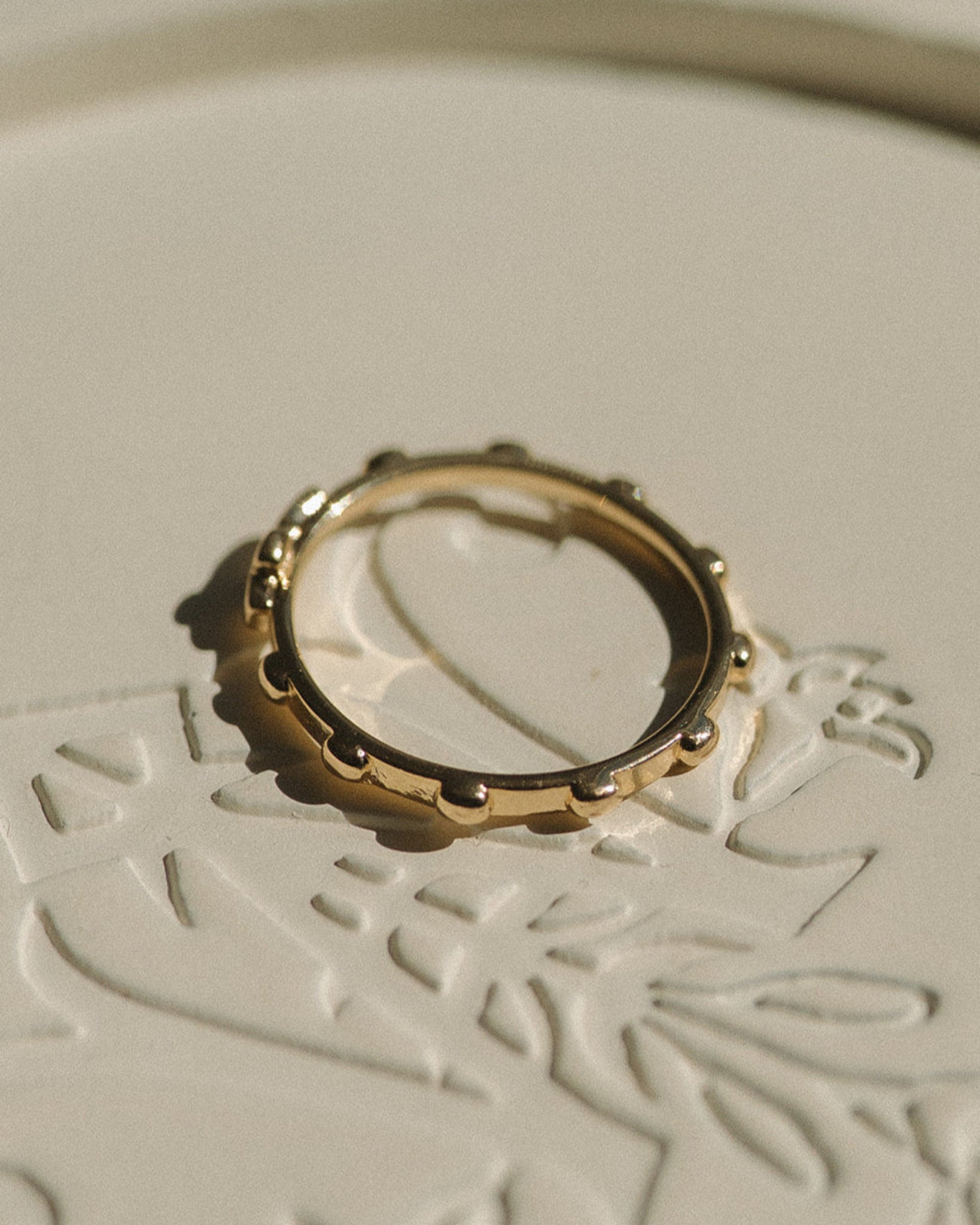 Gold rosary ring on a textured white surface