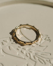 Gold rosary ring on a textured white surface