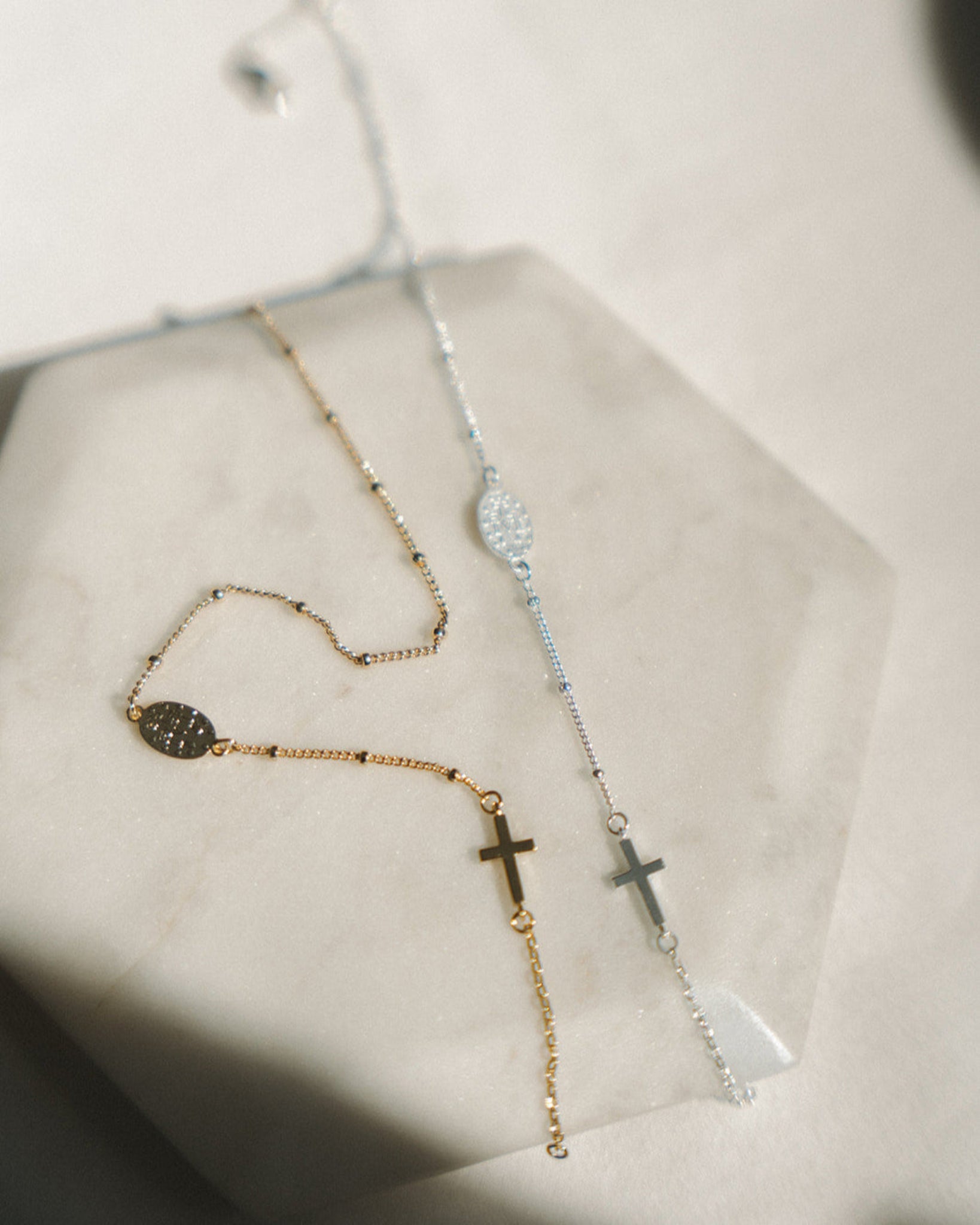 Two West Coast Catholic rosary bracelets with cross designs on a neutral background