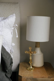Gold standing crucifix on a wooden nightstand beside lamp. 
