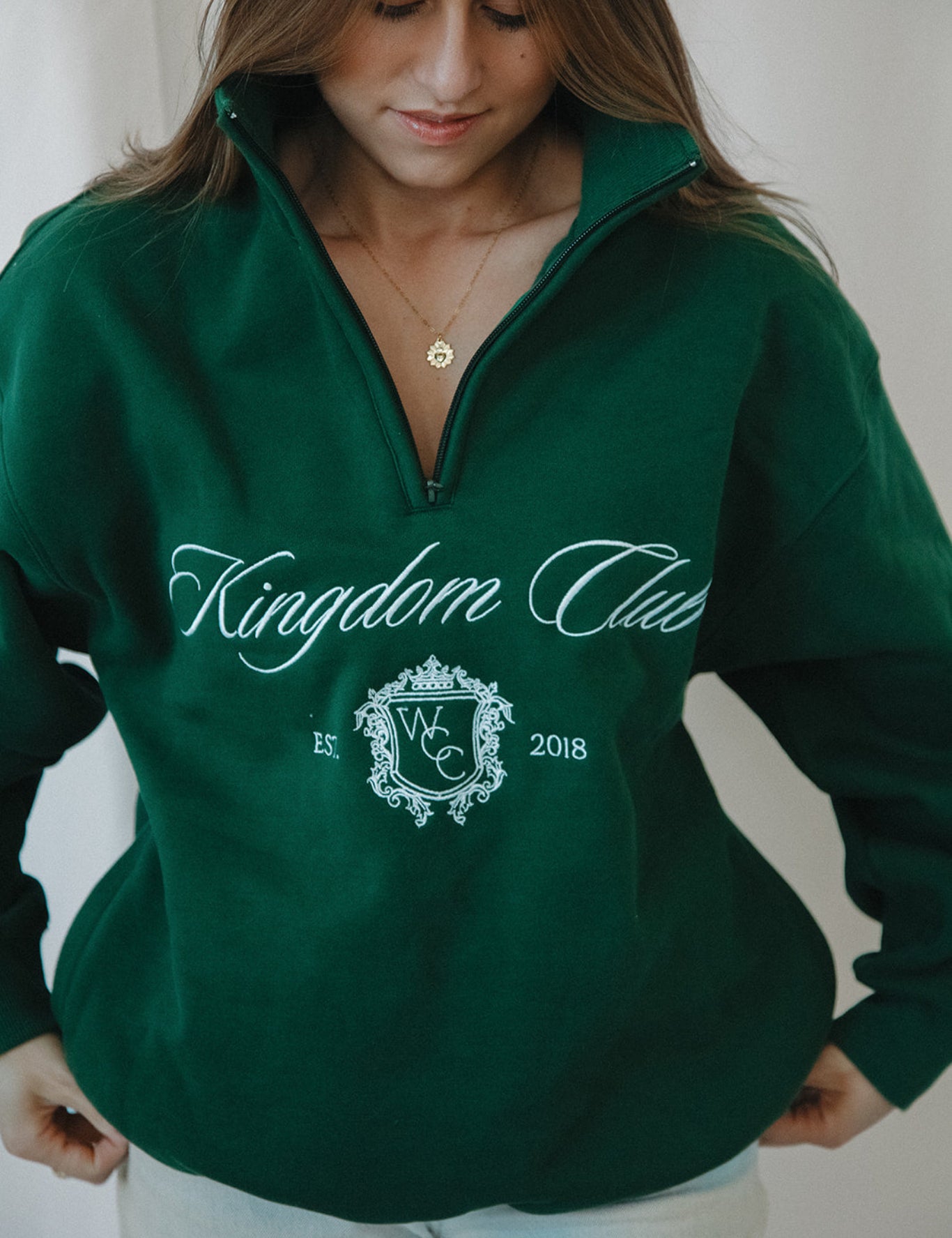 Person wearing a green 'Kingdom Club' sweatshirt with a logo and text.