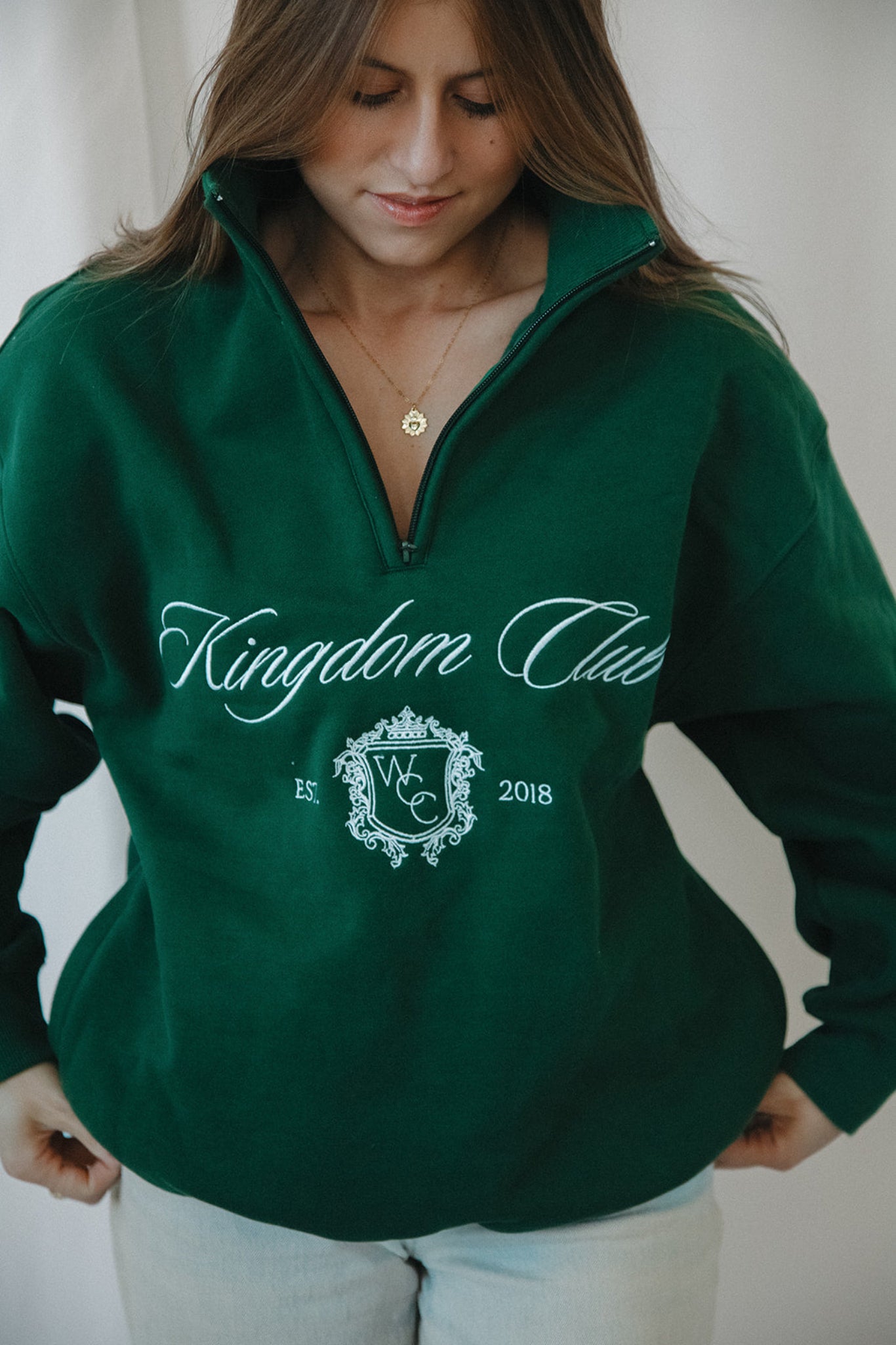Person wearing a green 'Kingdom Club' sweatshirt with a logo and text.