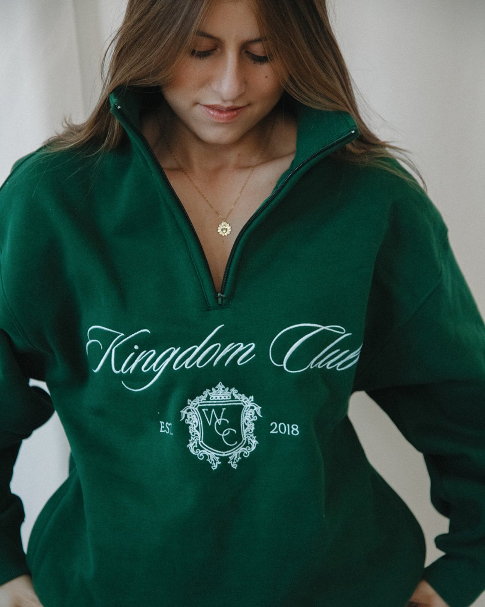 Person wearing a green 'Kingdom Club' sweatshirt with a logo and text.