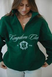 Person wearing a green 'Kingdom Club' sweatshirt with a logo and text.
