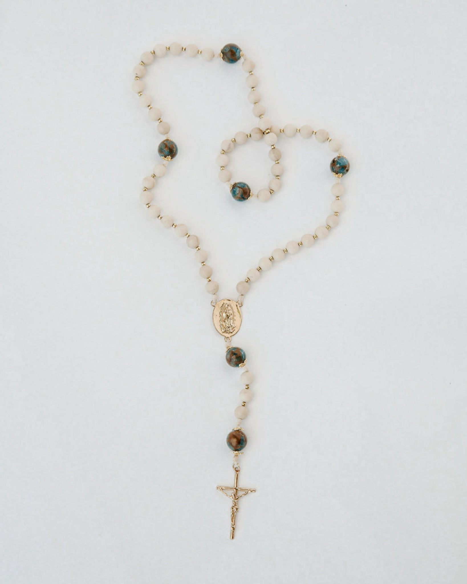 Rosary necklace with beads and a cross on a white background