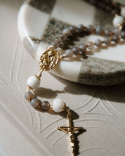 Durable catholic rosary with gold and white beads on a textured coffee table book.