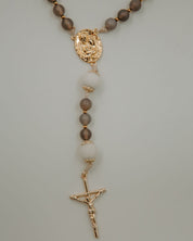 Holy Family Catholic rosary with brown and white beads and gold accents on a light gray background