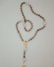 Rosary with brown beads and gold accents on a light gray background