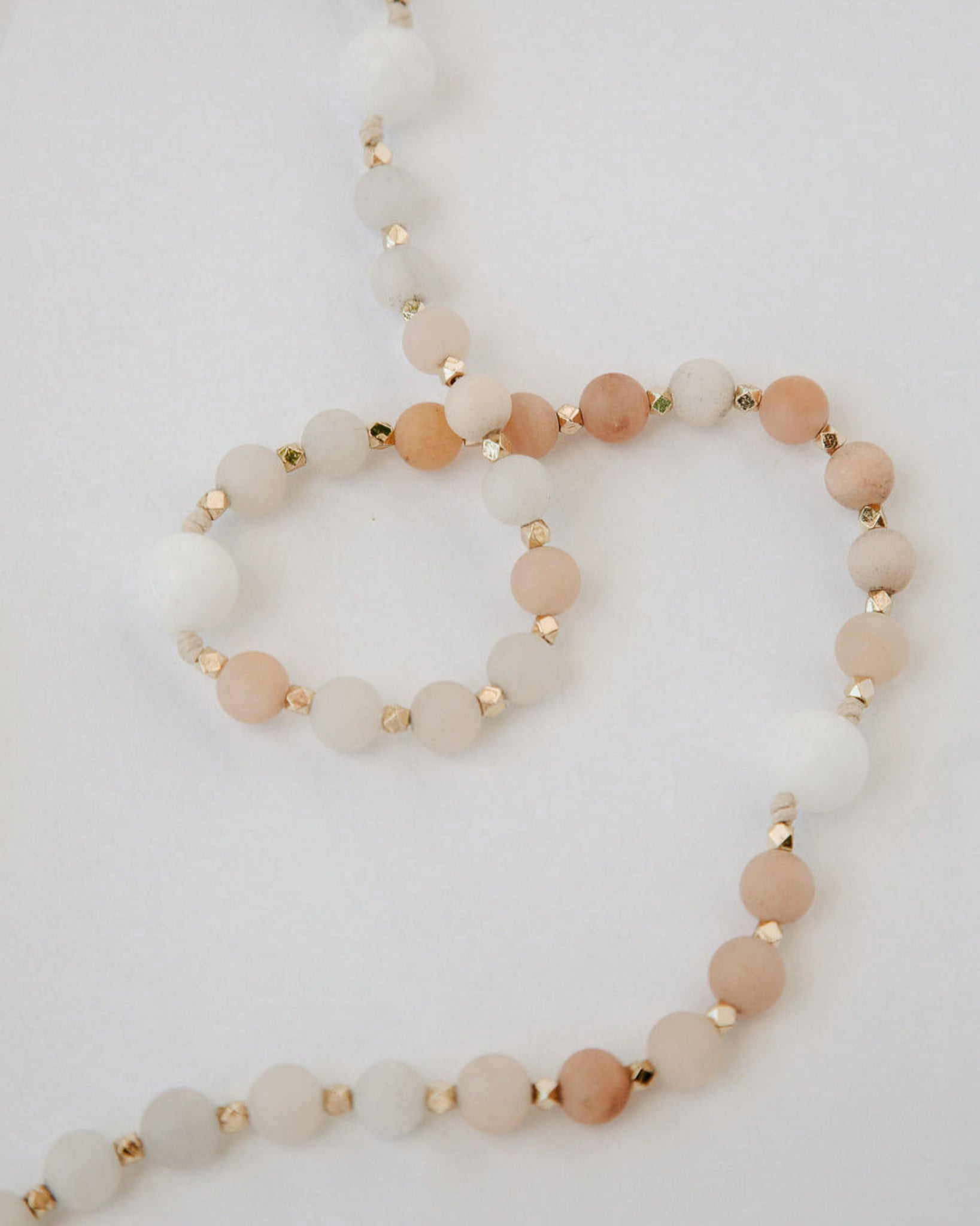 Pink and white immaculate heart rosary beads on white background