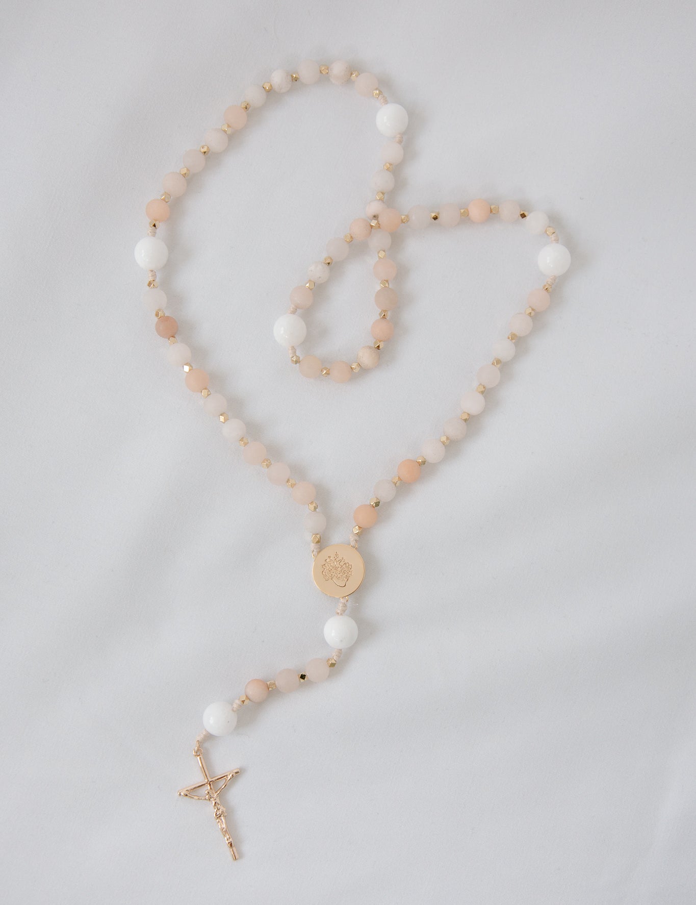 Pink and white immaculate heart rosary on white background
