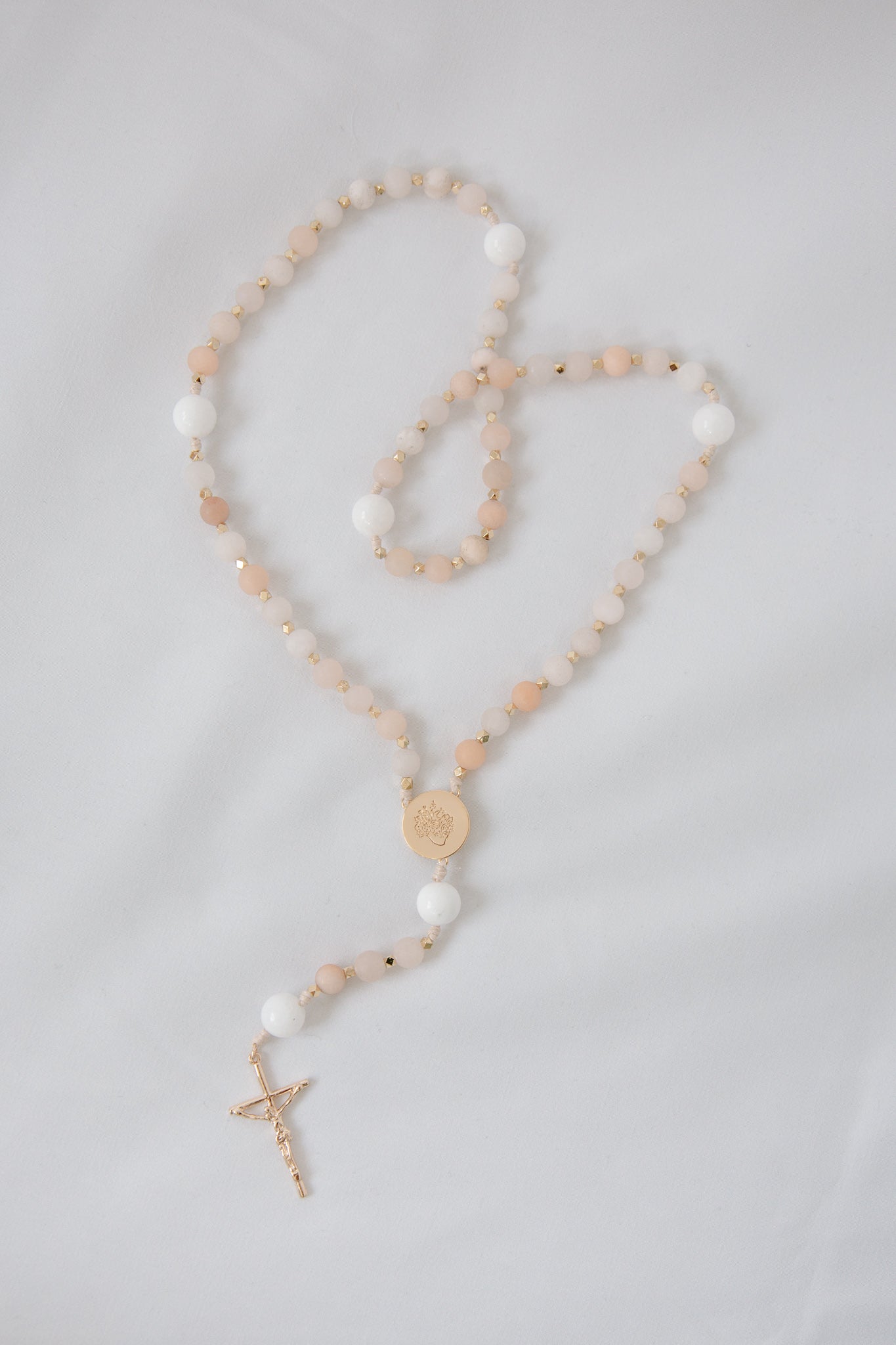 Pink and white immaculate heart rosary on white background
