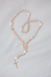 Pink and white immaculate heart rosary on white background
