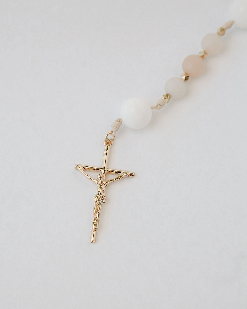 Pink and white immaculate heart rosary with gold cross on white background