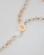 Pink and white immaculate heart rosary with gold medal on white background