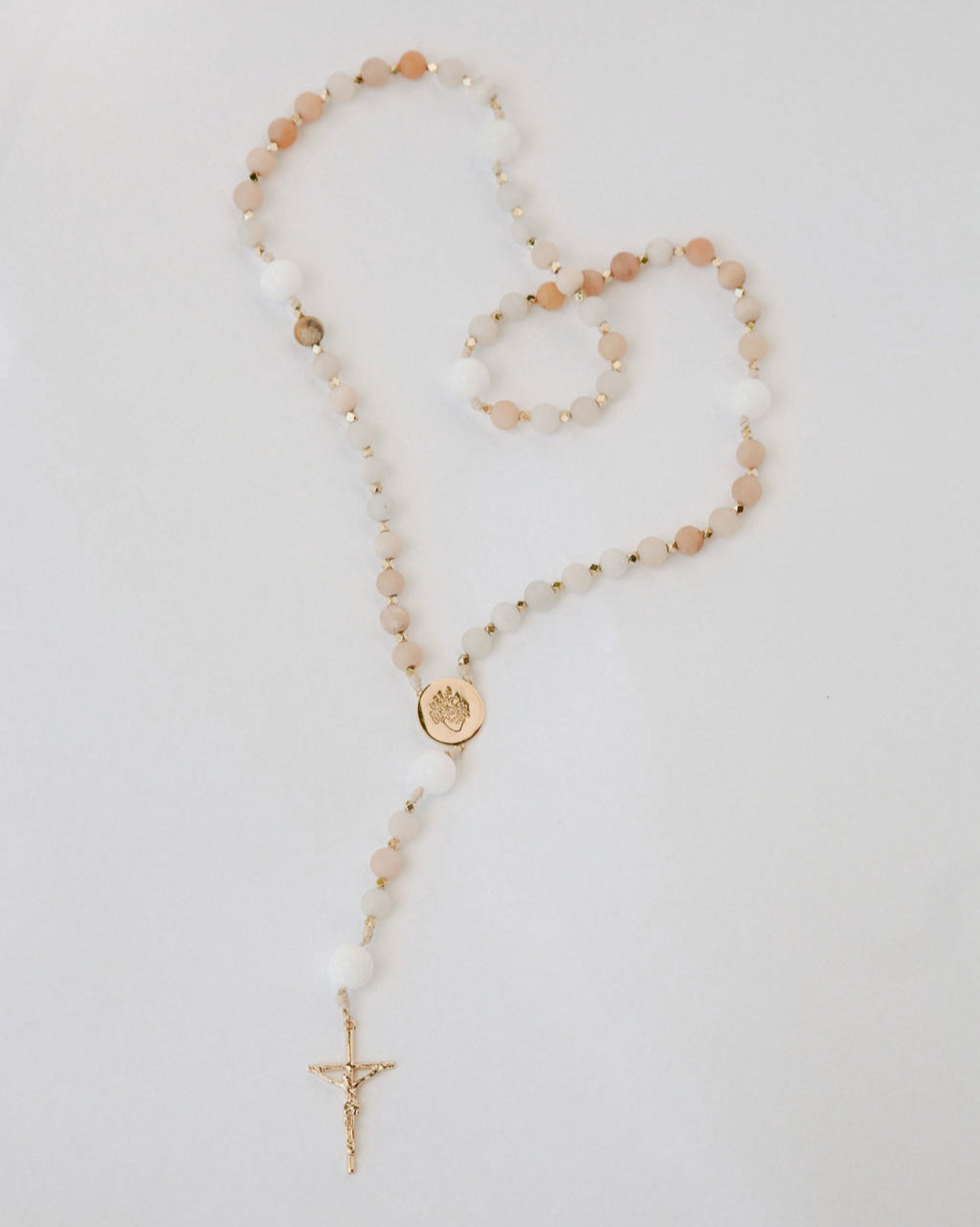 Pink and white immaculate heart rosary on white background
