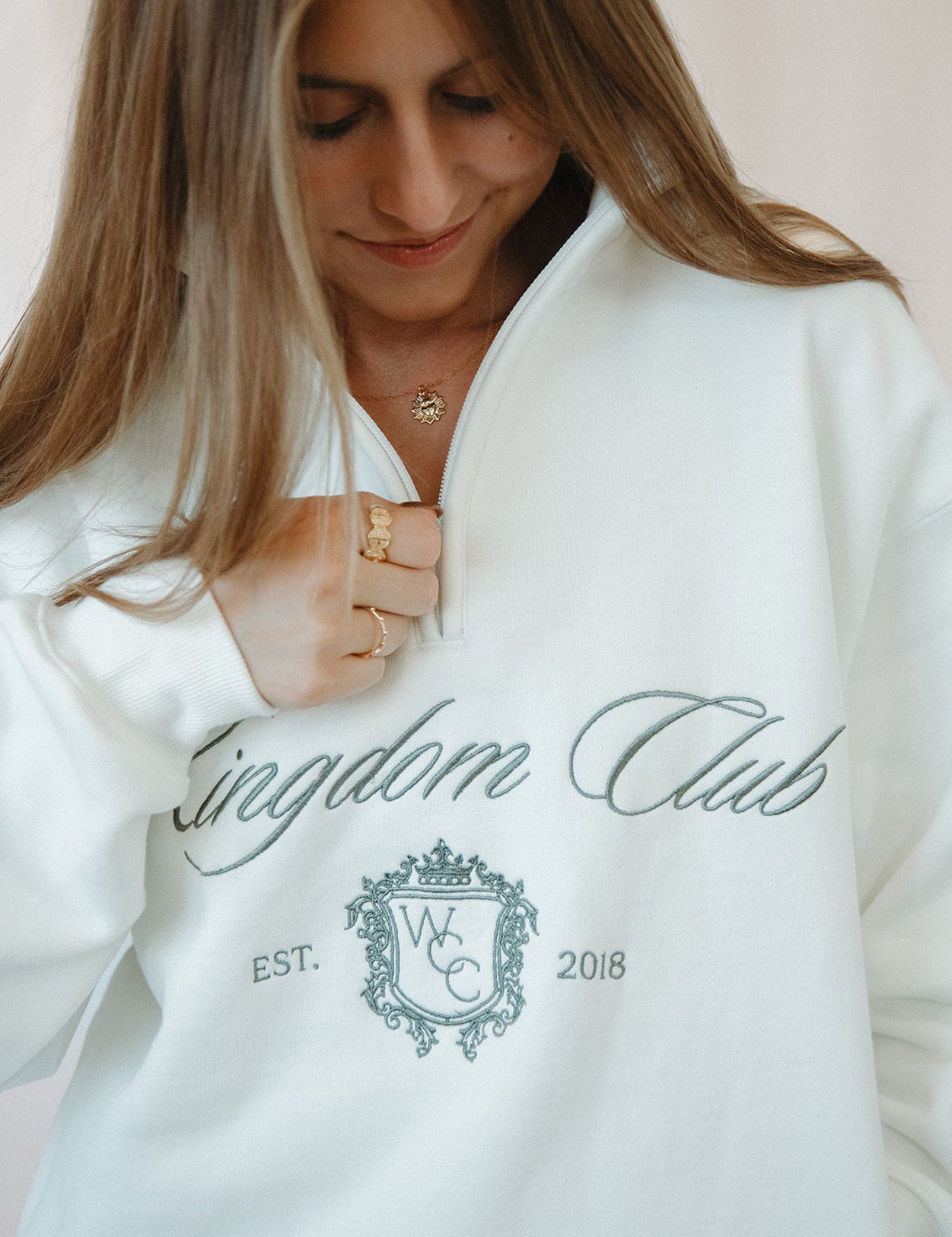 Person wearing a white sweatshirt with 'Kingdom Club' text and logo.