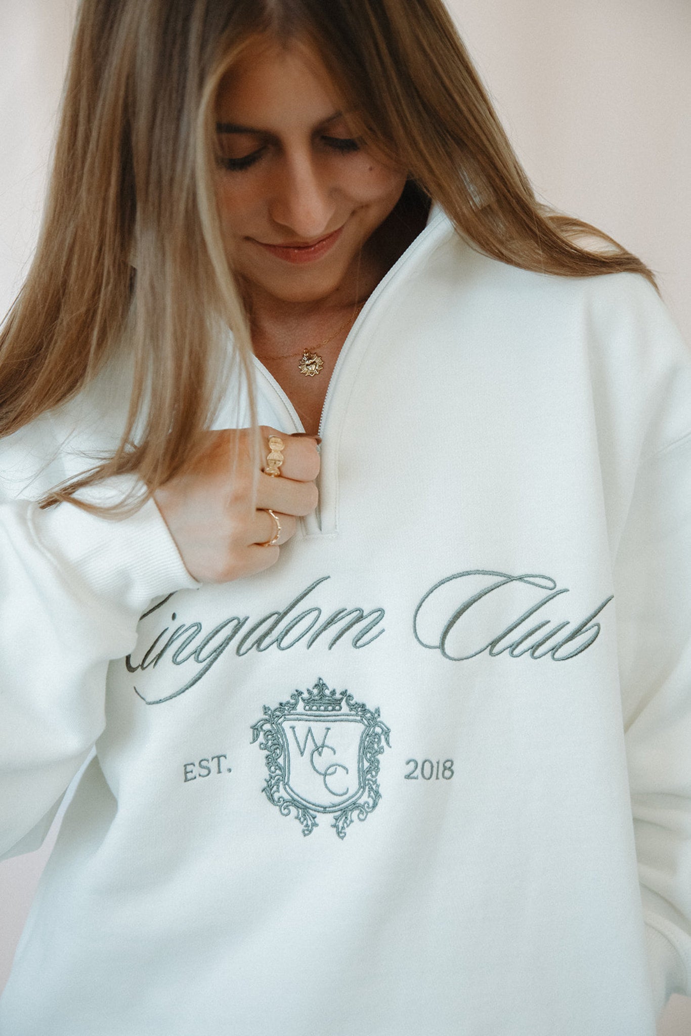 Person wearing a white sweatshirt with 'Kingdom Club' text and logo.