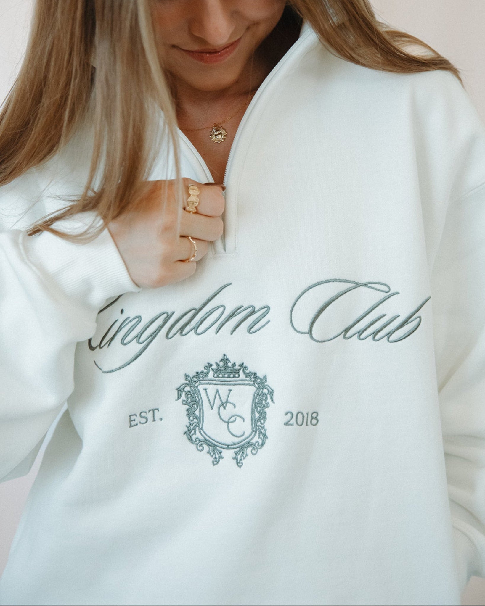 Person wearing a white sweatshirt with 'Kingdom Club' text and logo.