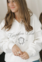 Person wearing a white hoodie with 'Kingdom Club' text and design.