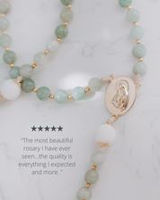 Green beaded rosary with a gold medal on a white background