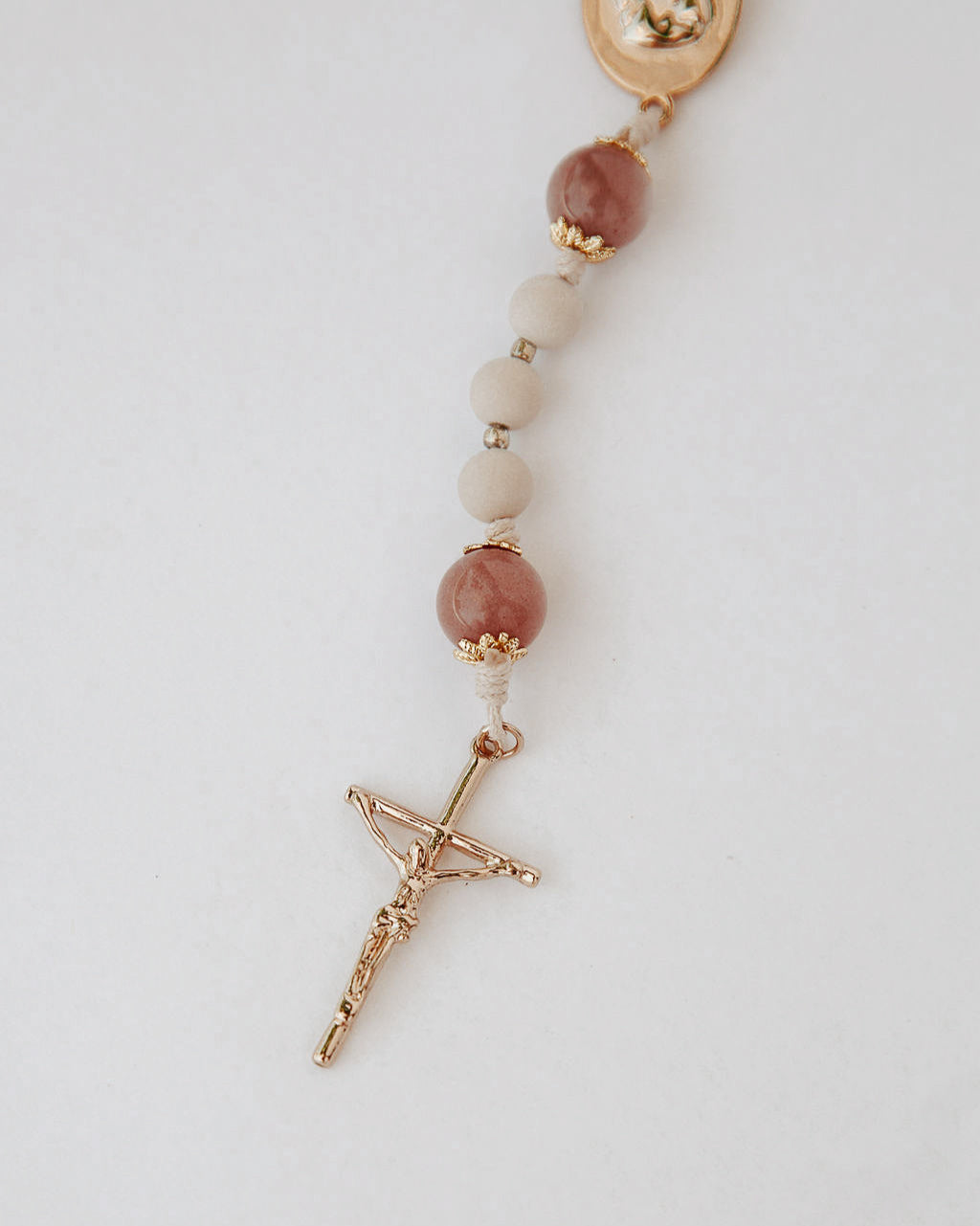 Close up of rosary with gold cross on white background