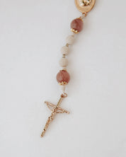 Close up of rosary with gold cross on white background