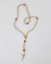 Rosary with beige and pink beads and a gold details on a light background