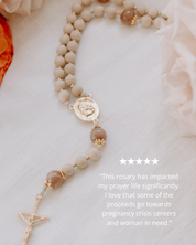 Rosary with beige and pink beads and a gold details on a light background with 5 star review